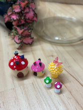 Load image into Gallery viewer, Mini fairy garden figurines sitting on a timber bench with glass jar and mini plants in the background.
